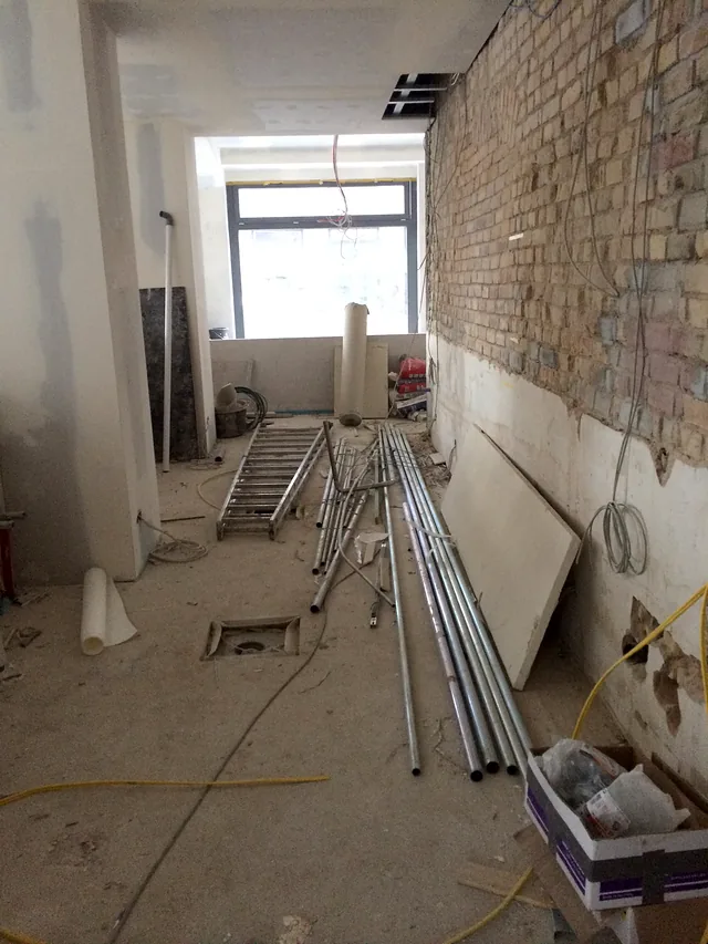 Guest room in shell state with exposed brick wall and materials on the floor